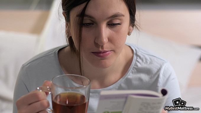 Green Tea Before Bed: Woman reading in bed with a cup of tea.